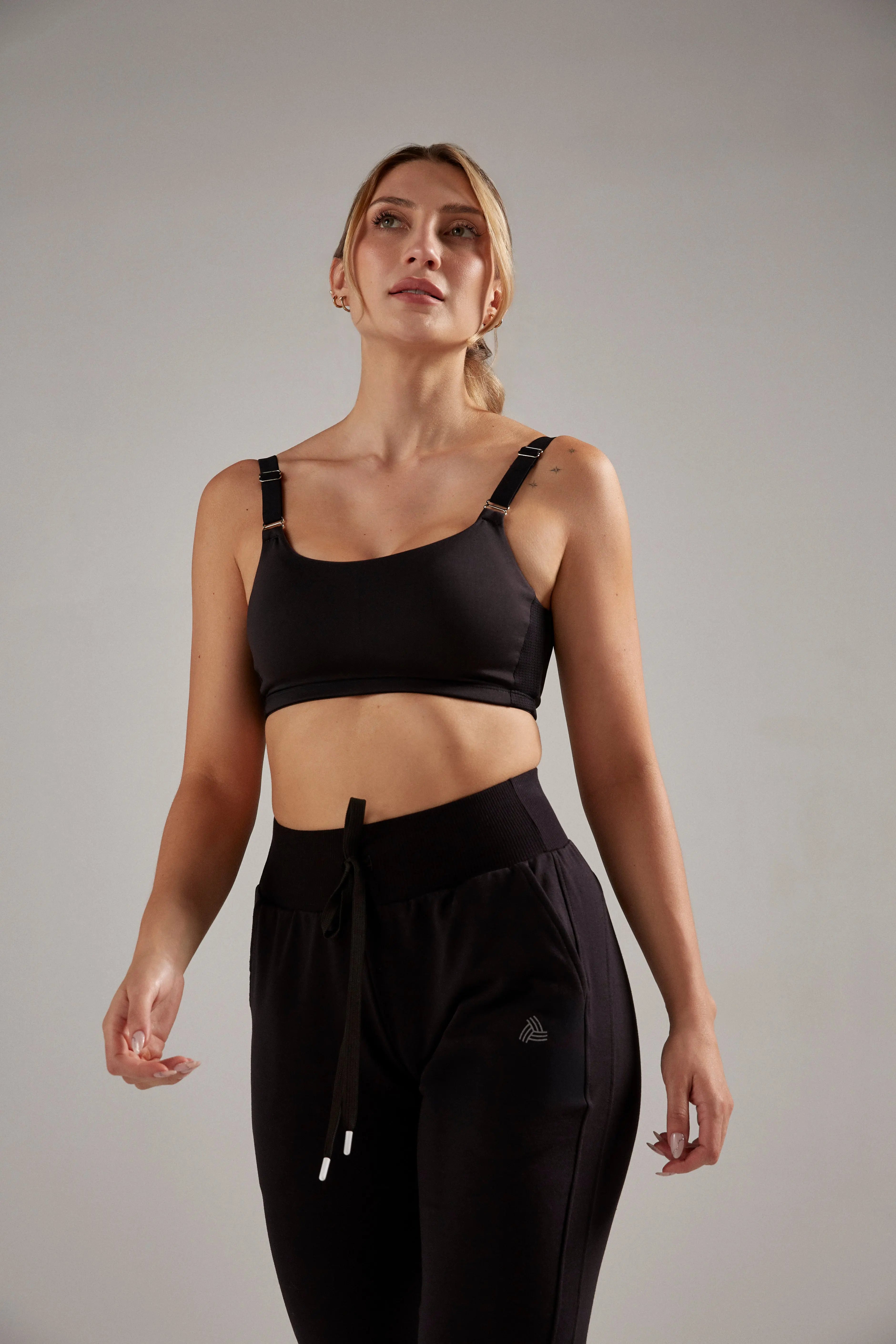 Top deportivo ajustado con cargaderas ajustables y GYO en espalda, color negro, modelo de cabello rubio