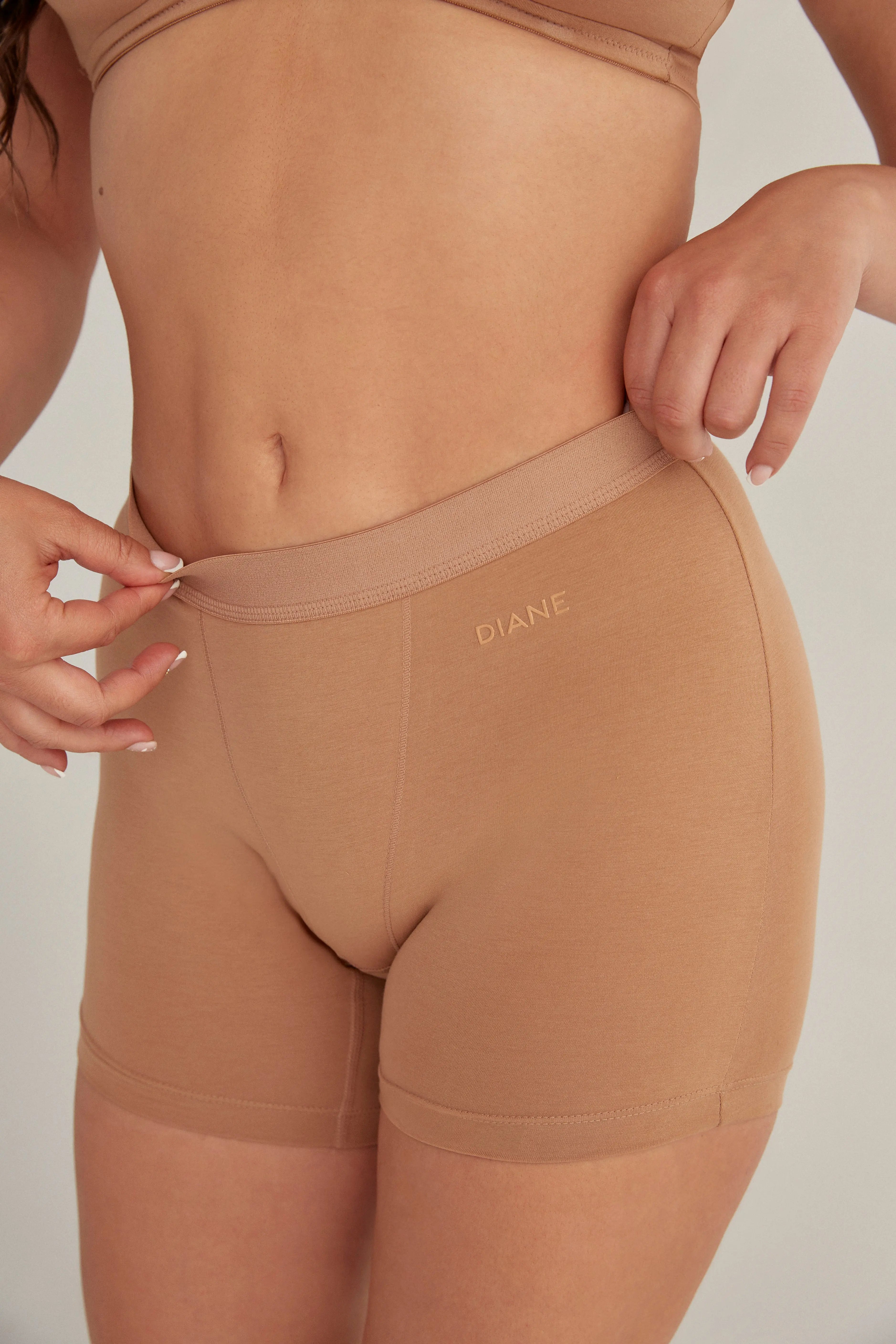 Panty cómodo con elástico ancho en cintura, color cafe, plano detalle, modelo de cabello rubio.