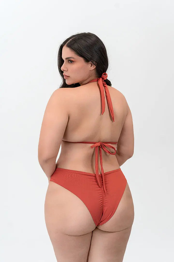 Modelo usando vestido de baño 2 piezas Diane & Geordi con panty tipo brasilera y recogido levanta cola, color arcilla de espalda 