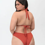 Modelo usando vestido de baño 2 piezas Diane & Geordi con panty tipo brasilera y recogido levanta cola, color arcilla de espalda 